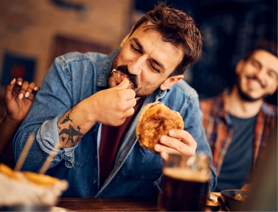 hungry-man-eating-burger-while-gathering-with-frie-2023-11-27-05-29-40-utc (1)